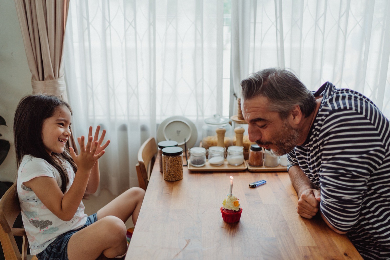Father and daughter at a table with a cupcake