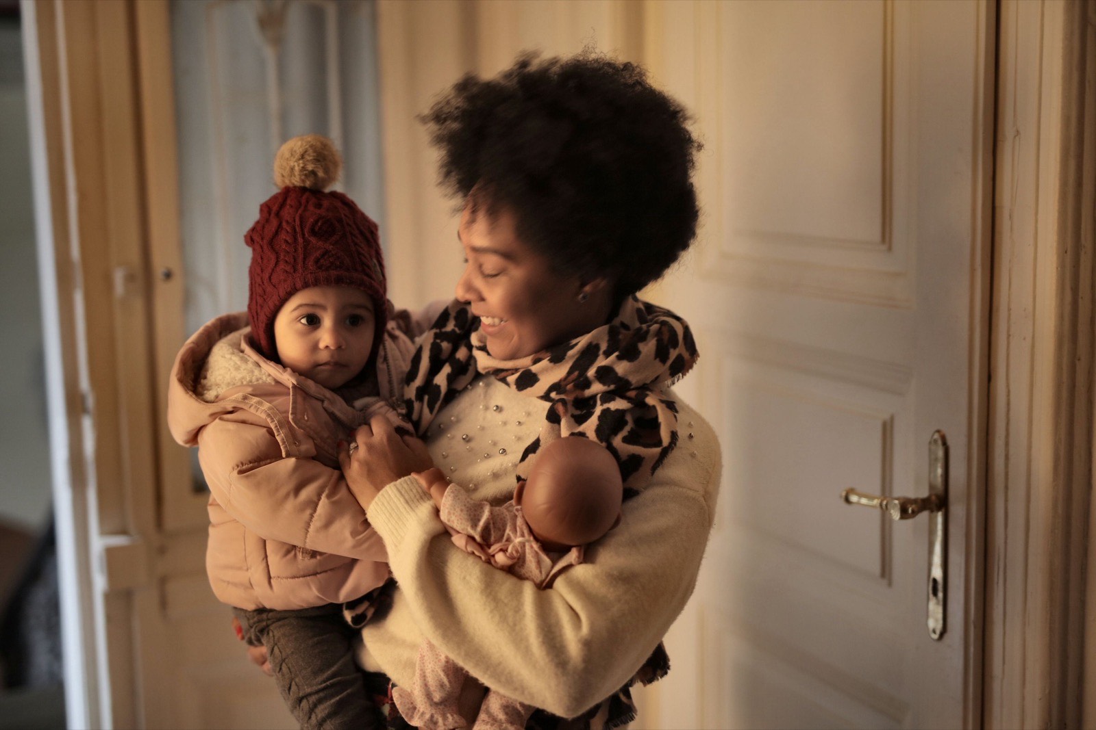 Woman holding a toddler by a cream doorway