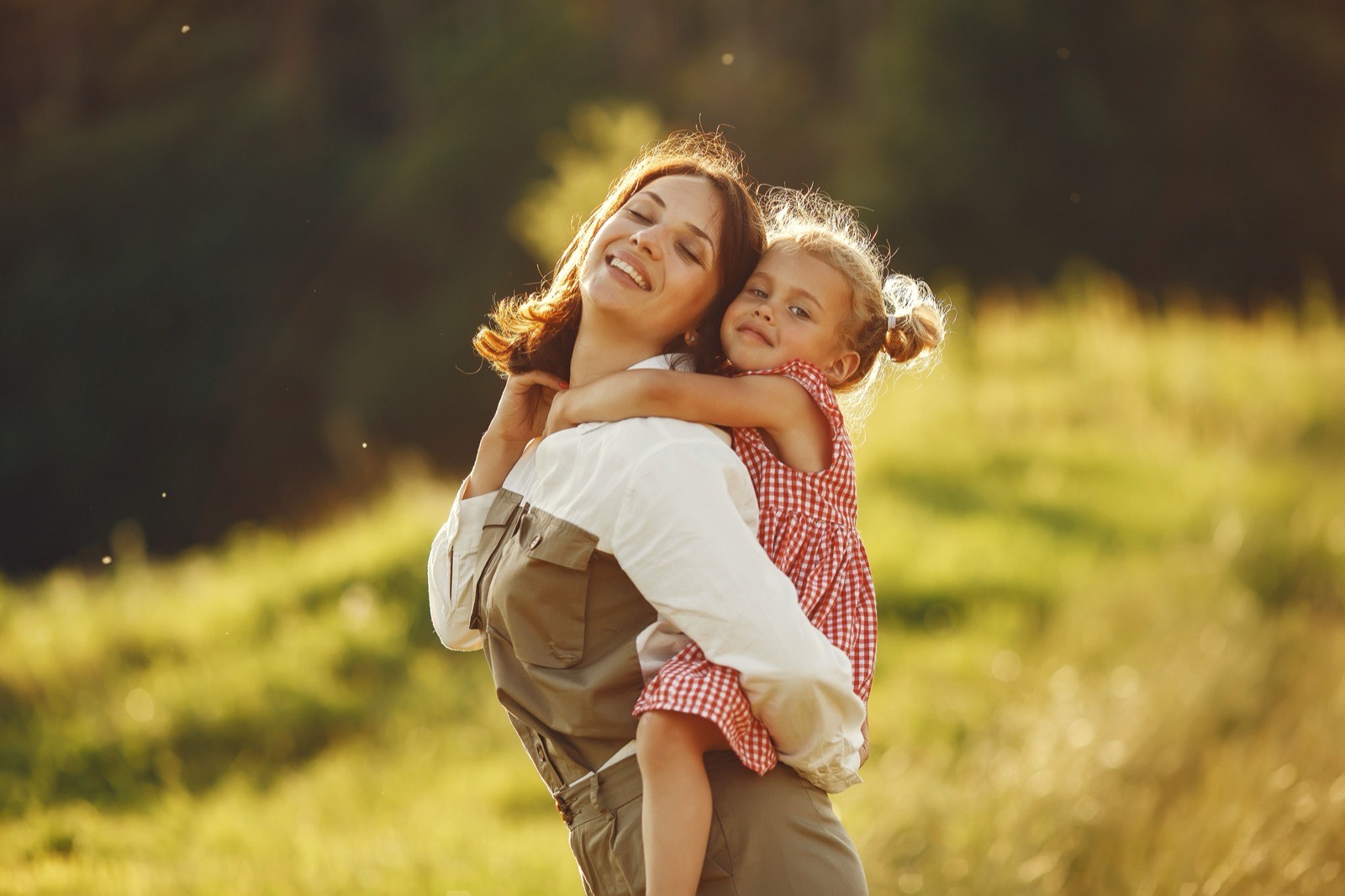 Mother carrying a child in evening light outdoors
