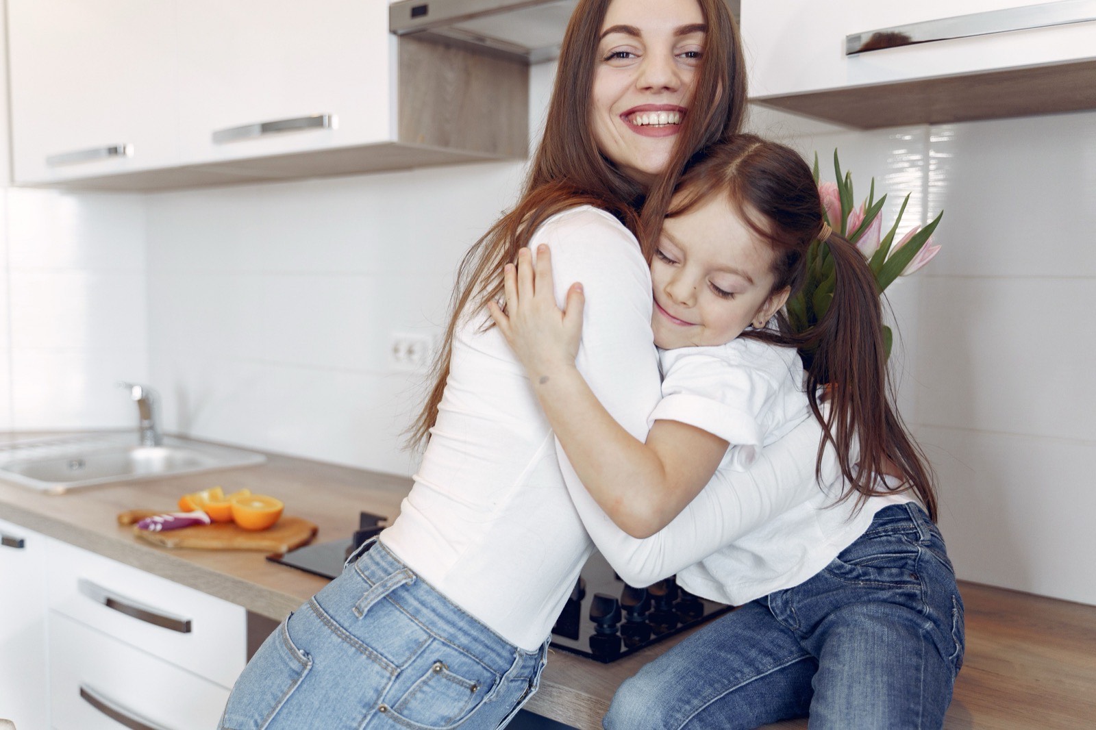 Mother and daughter hugging in a bright kitchen