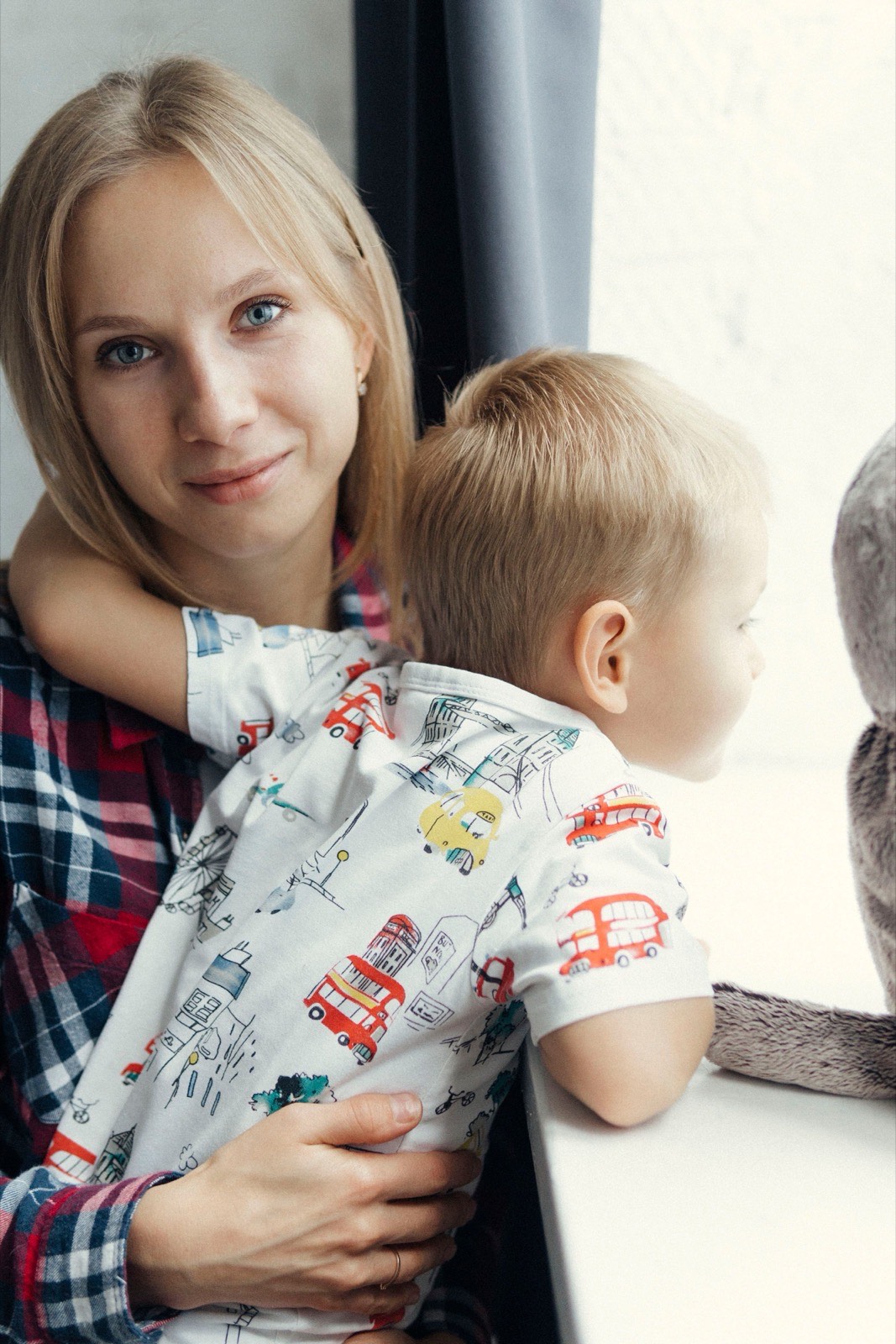 Woman holding a young boy by a bright window