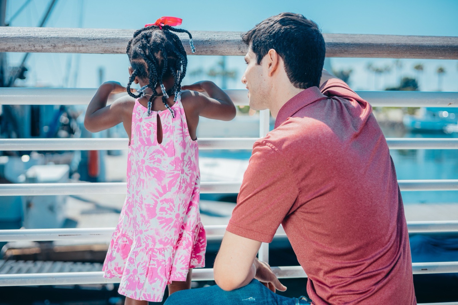 Adult and child at a marina railing overlooking boats